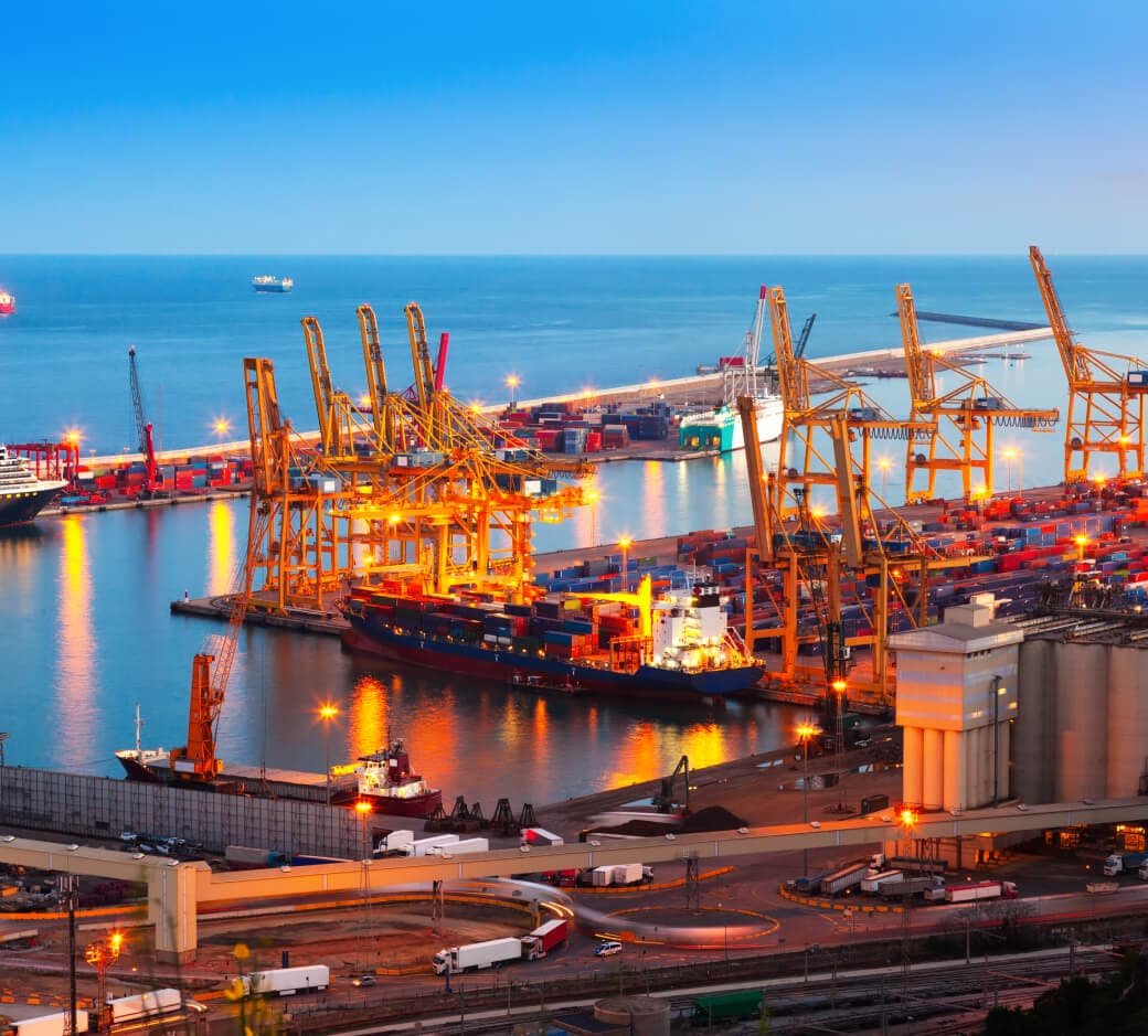 Container port at dusk with ships, cranes and freight traffic